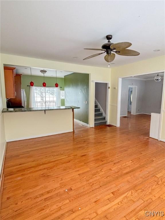 unfurnished living room featuring ceiling fan and light hardwood / wood-style floors