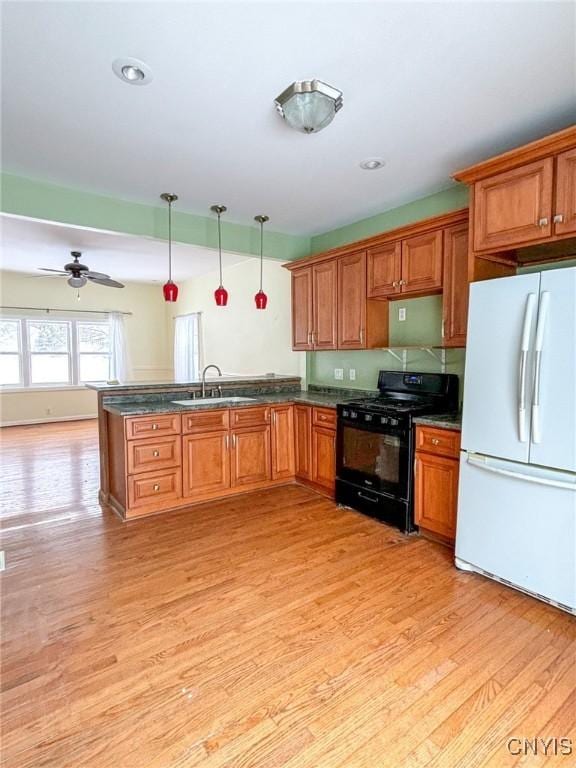 kitchen featuring ceiling fan, sink, white fridge, decorative light fixtures, and black range