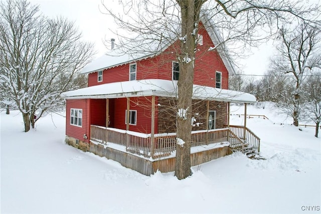 snow covered house featuring covered porch