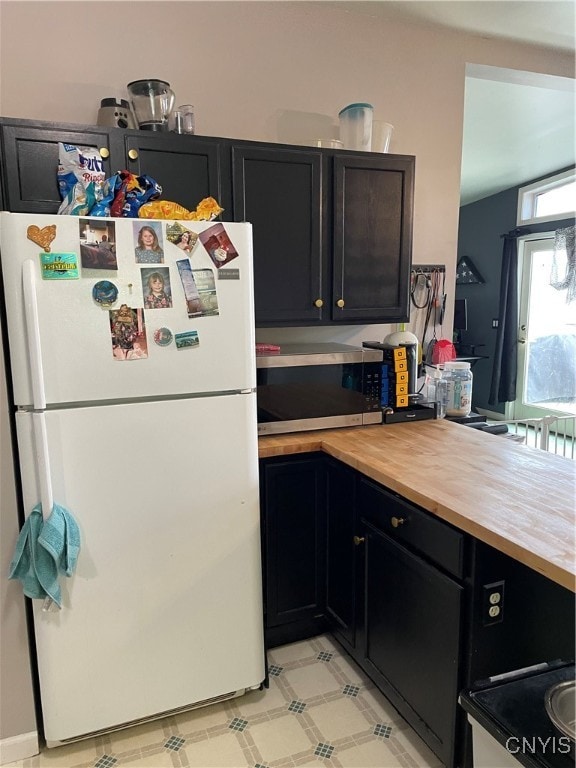 kitchen with butcher block counters and white fridge