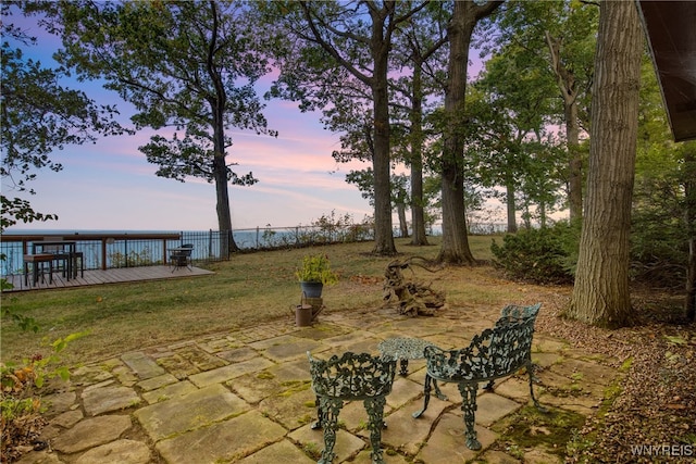 patio terrace at dusk with a yard and a deck