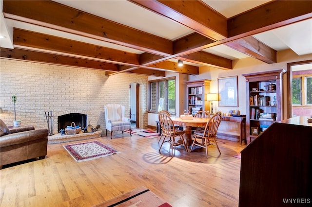 living room with plenty of natural light, light wood-type flooring, brick wall, and a brick fireplace