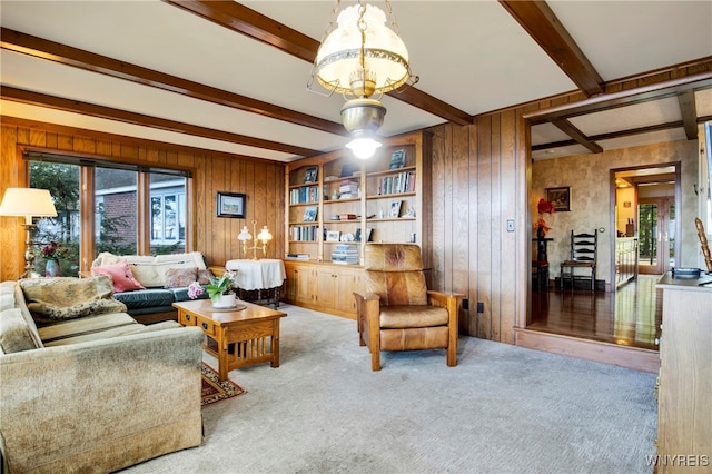 living room featuring carpet flooring, a notable chandelier, beam ceiling, and wooden walls