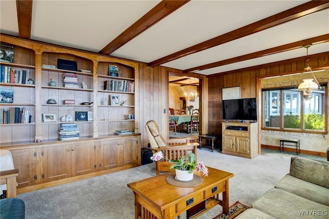 carpeted living room featuring wood walls, a notable chandelier, and beam ceiling