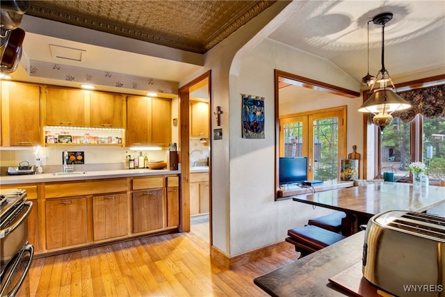 kitchen with stainless steel range with electric stovetop, french doors, ornamental molding, decorative light fixtures, and light hardwood / wood-style floors