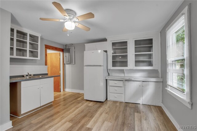 kitchen with light wood-type flooring, sink, white cabinets, white fridge, and ceiling fan