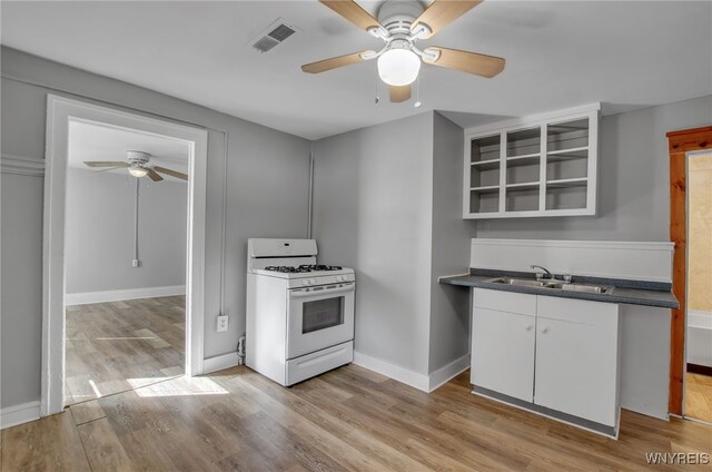 kitchen with light hardwood / wood-style floors, white cabinets, white range with gas stovetop, ceiling fan, and sink