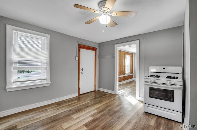 kitchen featuring white range with gas cooktop, hardwood / wood-style floors, and ceiling fan