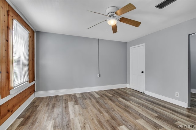 empty room with ceiling fan, plenty of natural light, and hardwood / wood-style floors