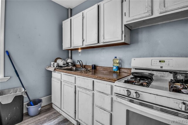 kitchen featuring light hardwood / wood-style flooring, sink, white gas range, and white cabinetry