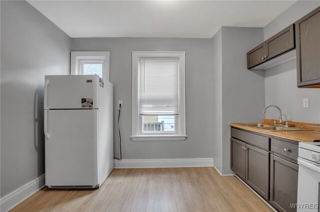 kitchen featuring white appliances, sink, and light hardwood / wood-style flooring