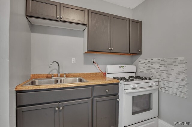 kitchen with decorative backsplash, gray cabinetry, sink, and gas range gas stove