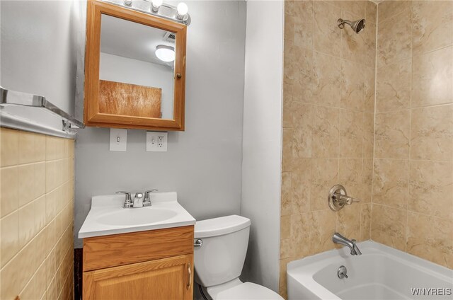 full bathroom featuring tiled shower / bath combo, vanity, and toilet