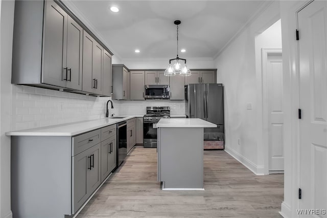 kitchen featuring appliances with stainless steel finishes, gray cabinetry, pendant lighting, light hardwood / wood-style flooring, and a center island