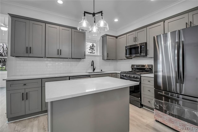 kitchen with gray cabinetry, a center island, hanging light fixtures, sink, and appliances with stainless steel finishes