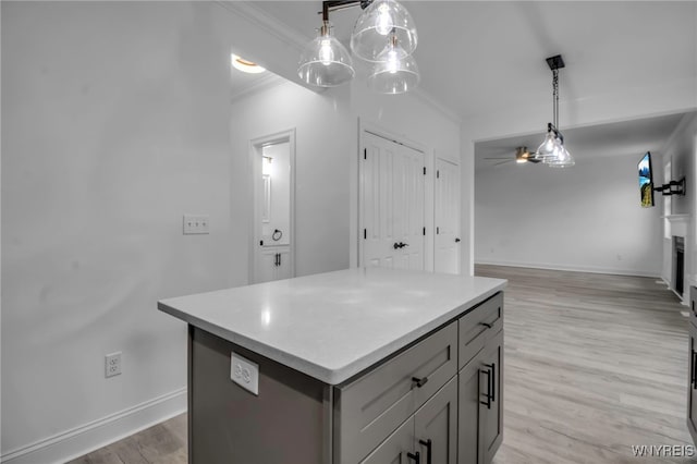 kitchen with decorative light fixtures, light hardwood / wood-style floors, a kitchen island, and crown molding