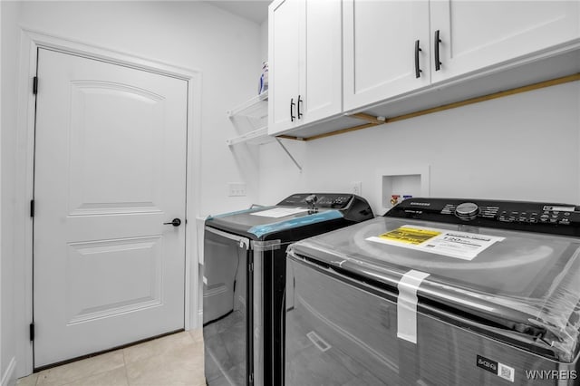 clothes washing area with cabinets, washing machine and dryer, and light tile patterned flooring