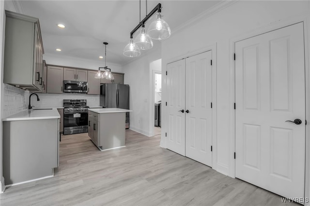 kitchen with pendant lighting, a center island, sink, appliances with stainless steel finishes, and light hardwood / wood-style floors