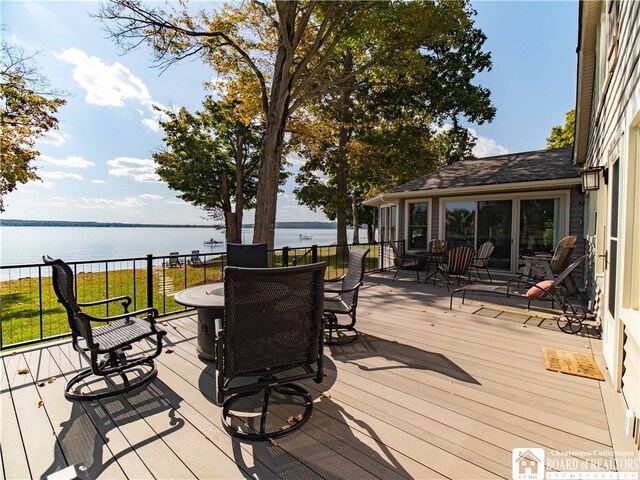 wooden deck featuring a water view and outdoor dining space