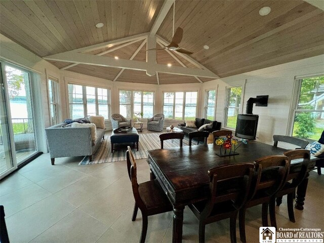 dining space featuring wooden ceiling, a wood stove, a healthy amount of sunlight, and lofted ceiling with beams