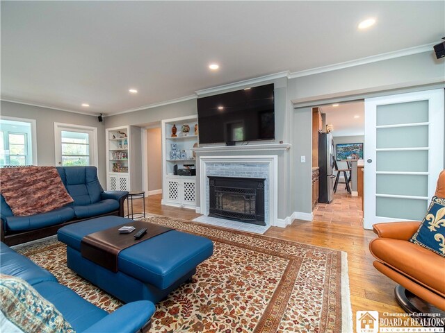 living area featuring a fireplace with flush hearth, recessed lighting, crown molding, and wood finished floors