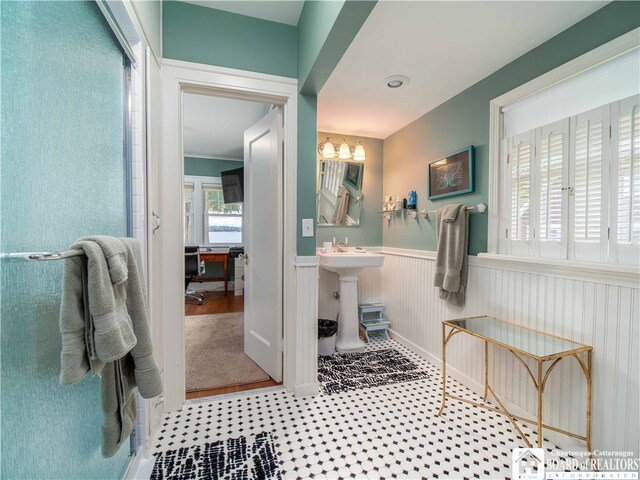 bathroom with a notable chandelier, a wainscoted wall, and a sink