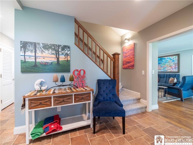 living area featuring stairs, baseboards, and stone finish flooring