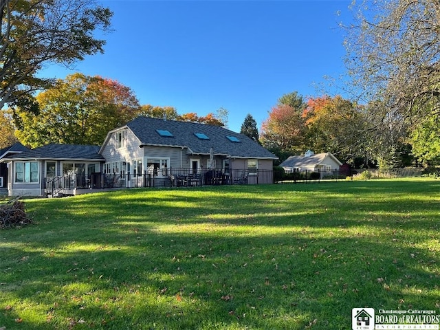 rear view of property with fence and a lawn