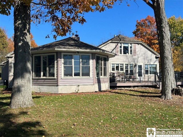 rear view of property with a lawn, a chimney, and a deck