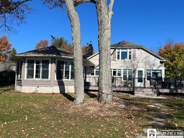 back of property featuring a wooden deck, a chimney, and a yard