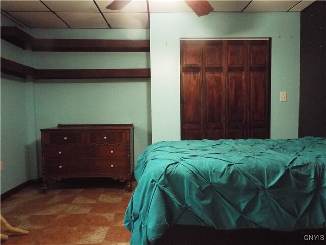 bedroom with a drop ceiling, ceiling fan, and a closet