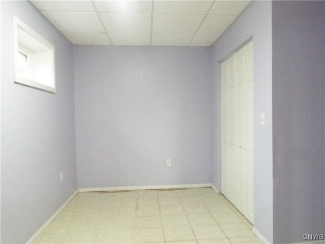 spare room with light tile patterned flooring and a drop ceiling