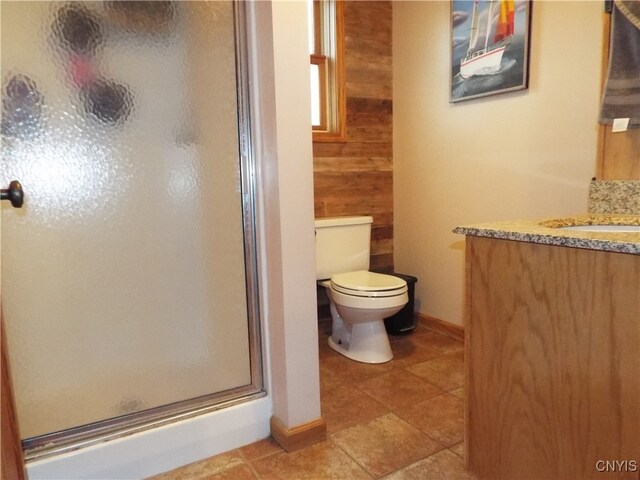 bathroom with an enclosed shower, wooden walls, tile patterned floors, vanity, and toilet