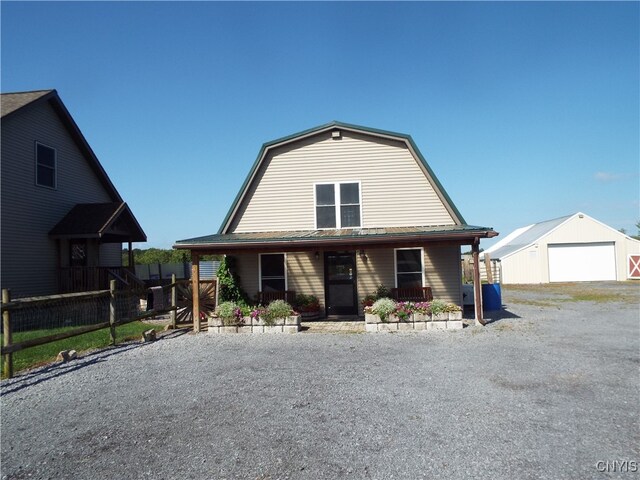 view of front of home featuring a garage, a porch, and an outbuilding