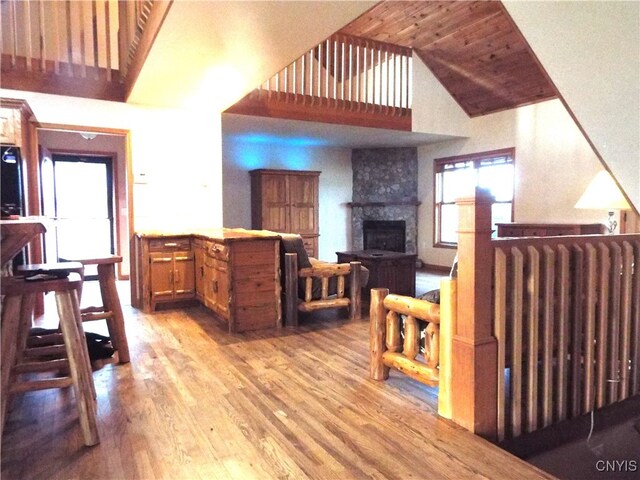 living room with radiator heating unit, light wood-type flooring, high vaulted ceiling, and a large fireplace