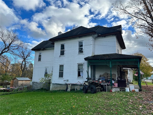 back of property featuring a storage shed and a yard