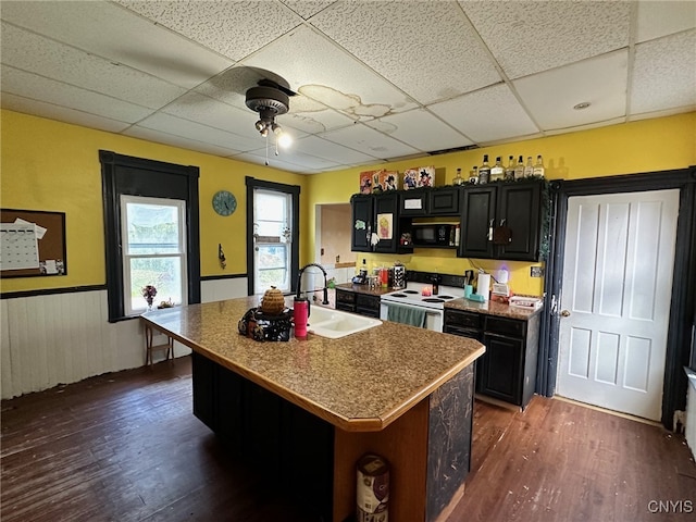 kitchen featuring dark wood-type flooring, a center island with sink, and white range with electric stovetop