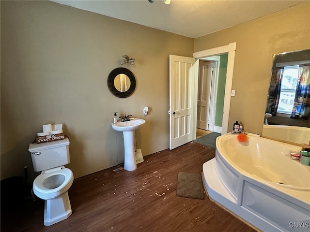 bathroom with a washtub, toilet, sink, and hardwood / wood-style flooring