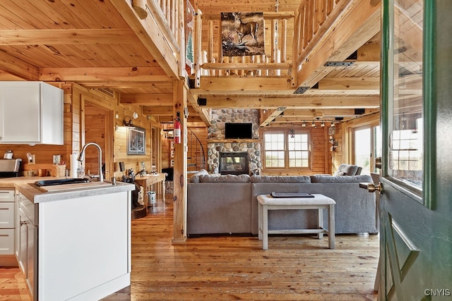 interior space featuring light wood-type flooring, wood counters, sink, white cabinets, and wooden walls