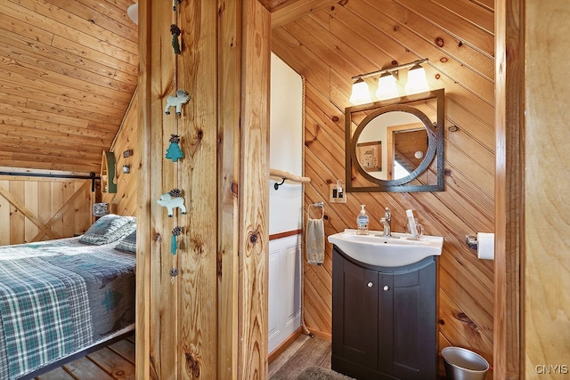 bathroom featuring vanity, wooden walls, and vaulted ceiling