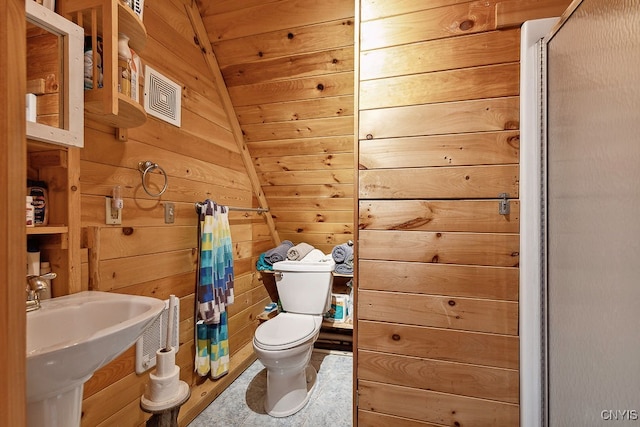 bathroom with lofted ceiling, wood walls, sink, curtained shower, and toilet