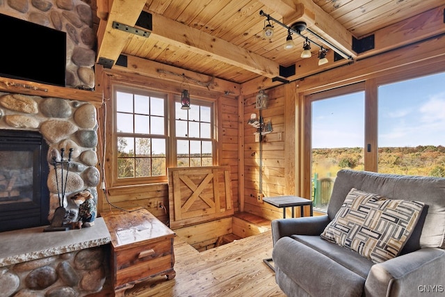 living area featuring wood ceiling, plenty of natural light, hardwood / wood-style floors, and a stone fireplace