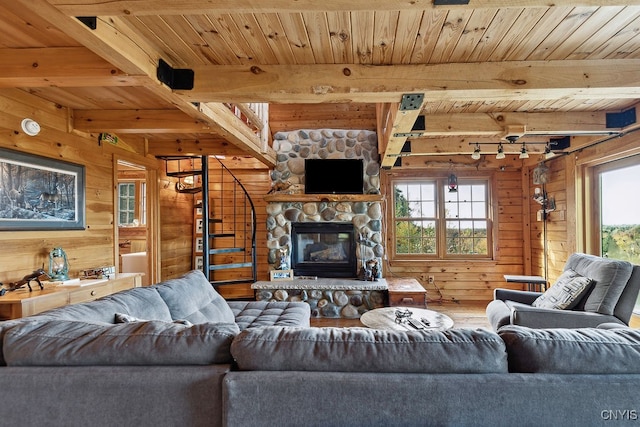 living room featuring wood walls, beamed ceiling, wooden ceiling, and a fireplace