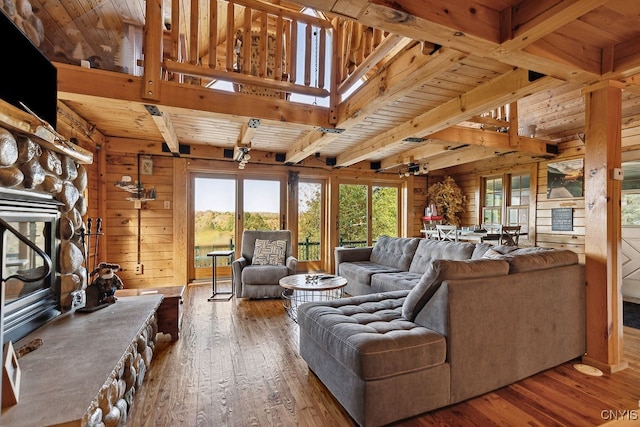 living room featuring wood ceiling, hardwood / wood-style flooring, and a stone fireplace