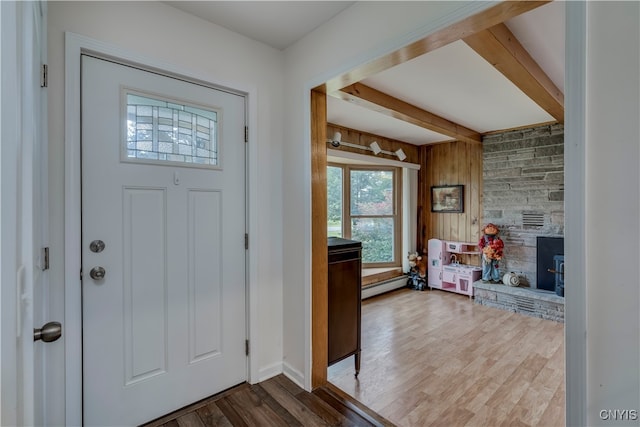 foyer entrance featuring a fireplace, wood walls, beamed ceiling, and hardwood / wood-style flooring