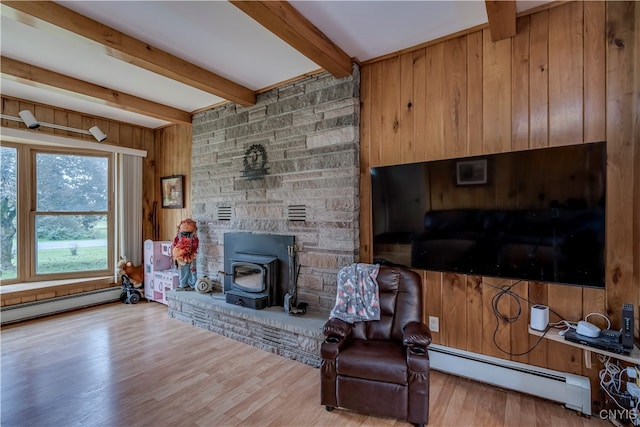 living room with a wood stove, beam ceiling, baseboard heating, and hardwood / wood-style floors