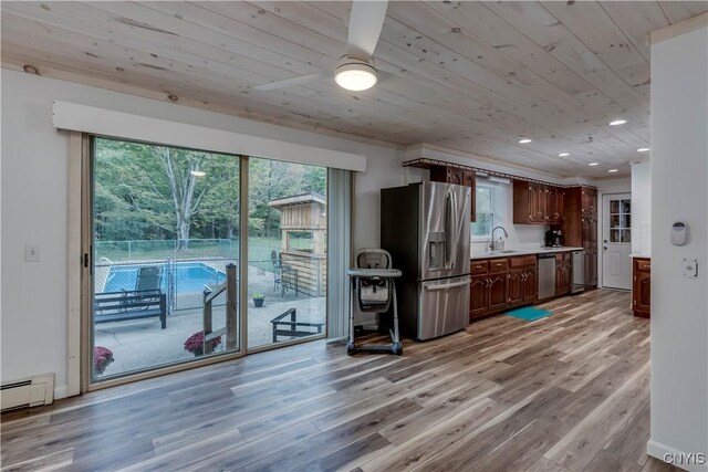kitchen featuring light countertops, stainless steel appliances, light wood finished floors, a baseboard radiator, and a sink