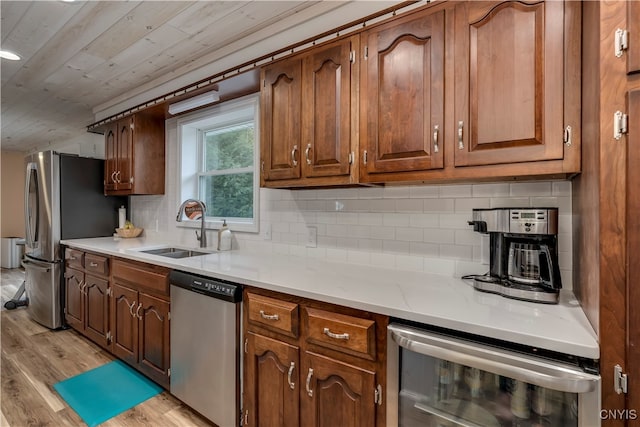 kitchen with sink, beverage cooler, light hardwood / wood-style flooring, backsplash, and appliances with stainless steel finishes