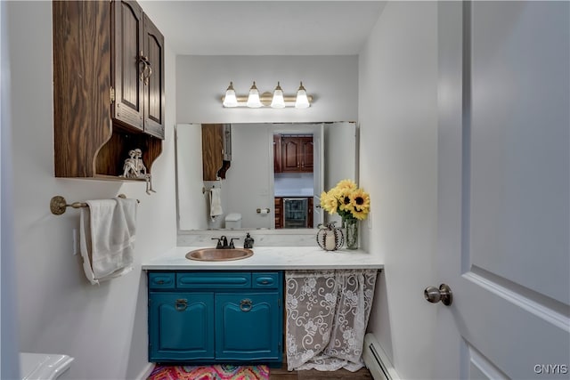 bathroom with vanity, toilet, and a baseboard heating unit