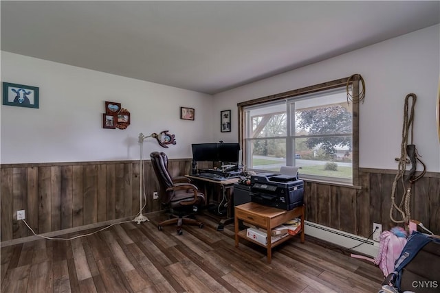 office area with wood finished floors, wood walls, a baseboard heating unit, and a wainscoted wall